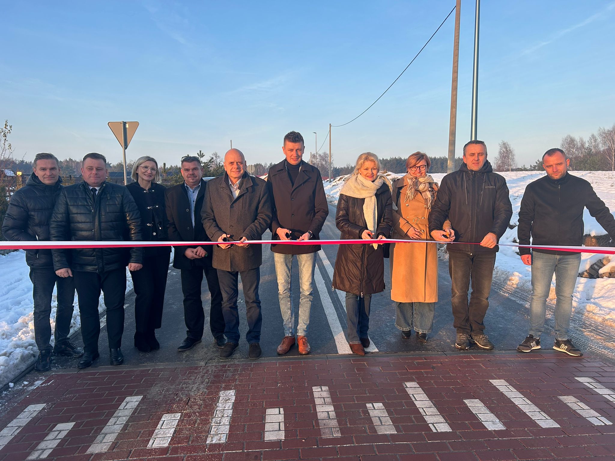 przedstawiciele władz rządowych oraz samorzadowych przecinajacy wstegę w zwiazku z otwarciem drogi. w tle widac nowowybudowana drogę
