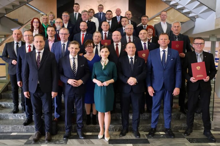 na zdjęciu przedstawieni są włodarze oraz skarbnicy gmin z wielkopolski z wojewodą wielkopolskim którzy podpisali umowy w ramach rządowego programu rozwoju dróg lokalnych, ustawieni oni sa kaskadow na schodach